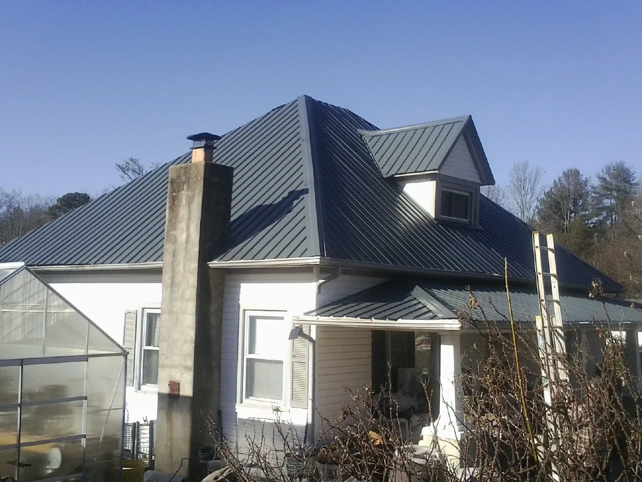 Dark blue standing seam metal roof on a white farmhouse with dormer — Slate & Tile Roof Repair by Roofing Brothers in Coventry