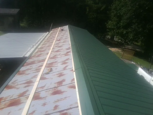 Old rusted panels beside newly installed green metal roofing — Wind Damage Roof Repair by Roofing Brothers in Coventry