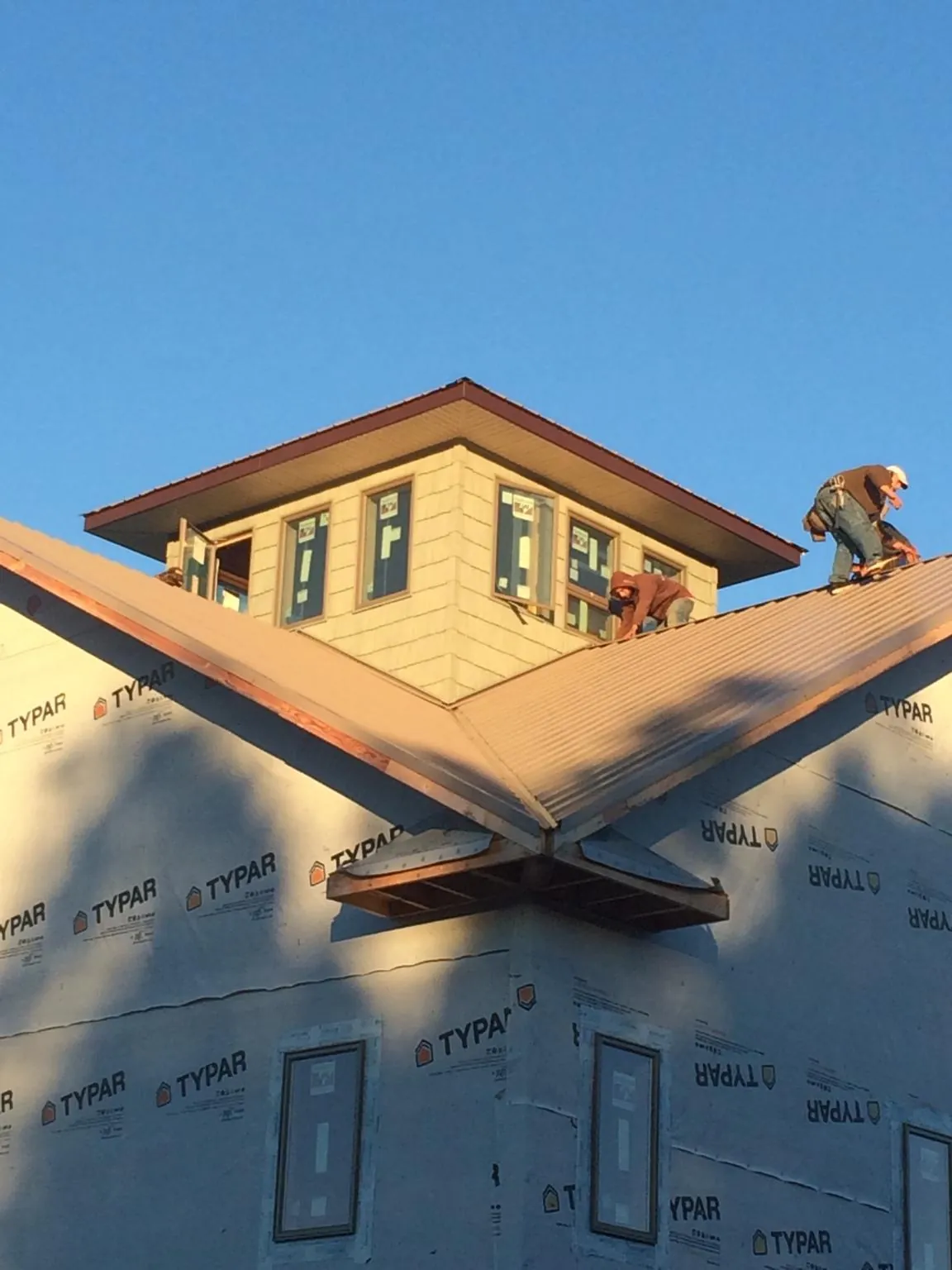 Roofers working around a rooftop cupola on a new metal roof at sunset — Roof Waterproofing in Coventry by Roofing Brothers